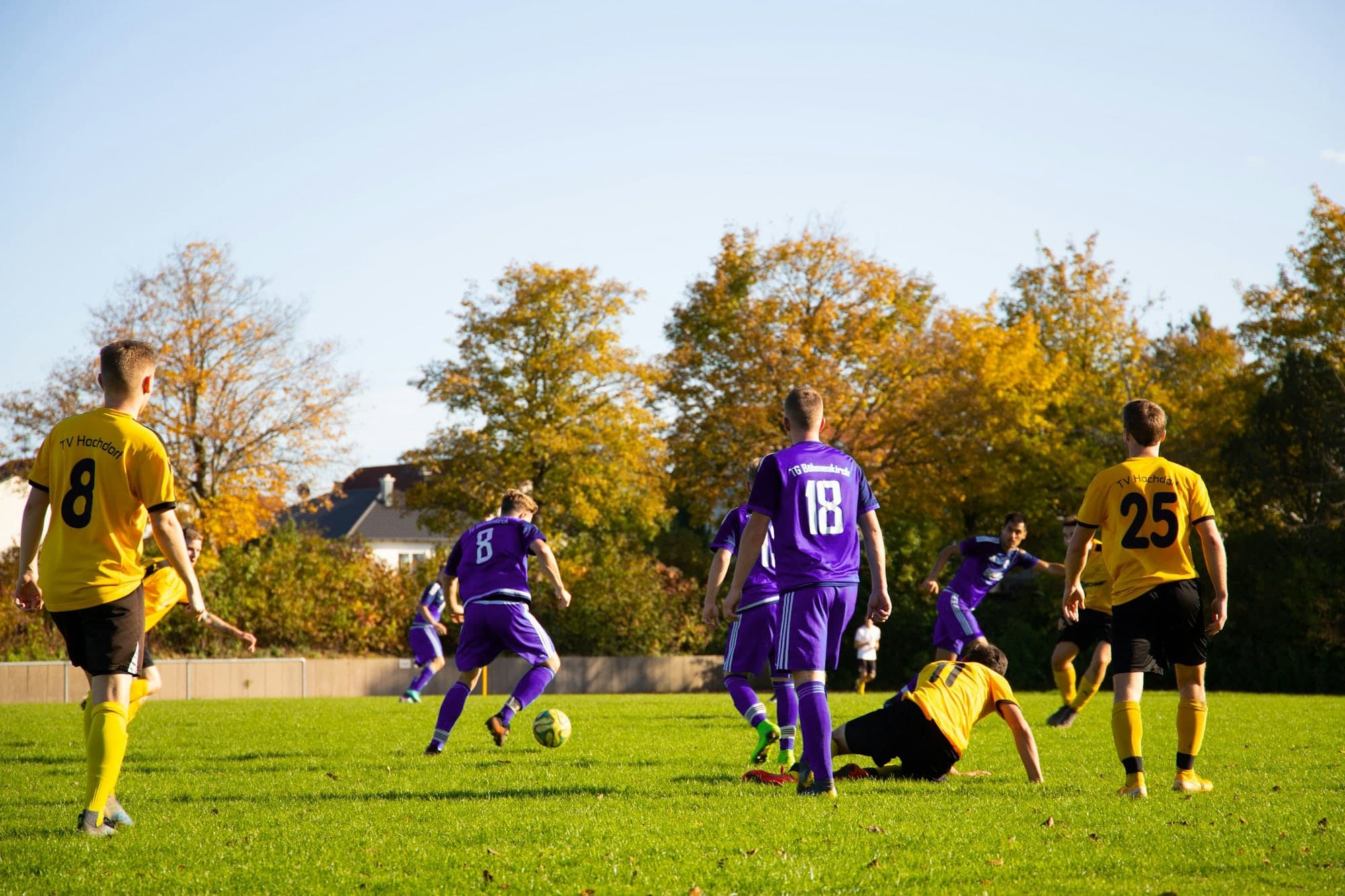 Match de football sur gazon, maillots violets contre maillots jaunes