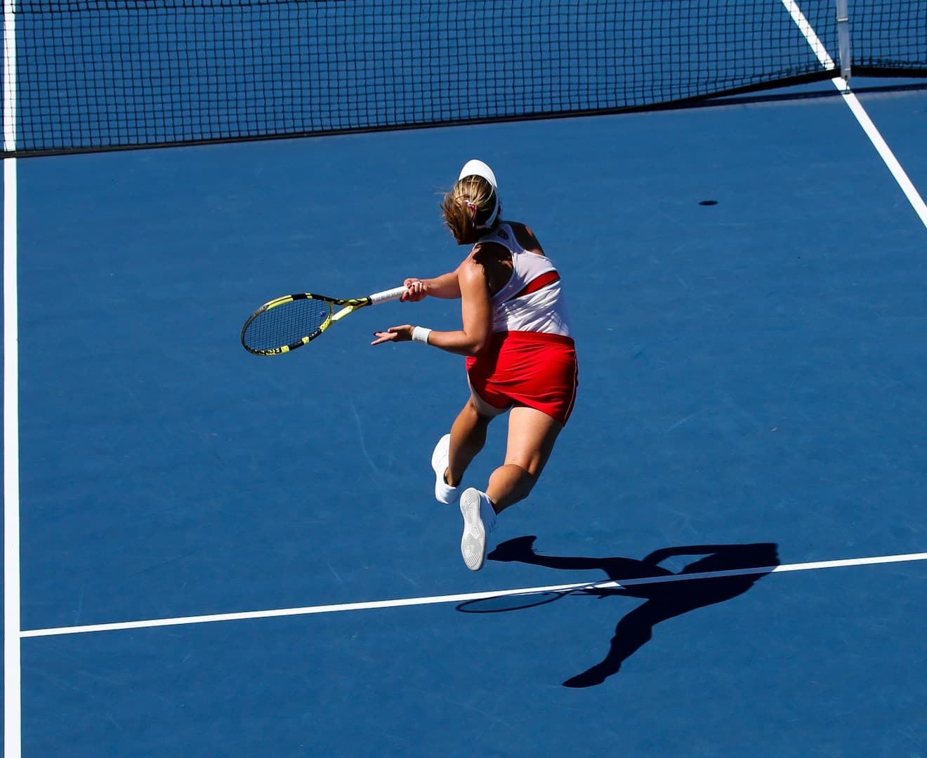 Joueuse de tennis en pleine frappe sur un court bleu